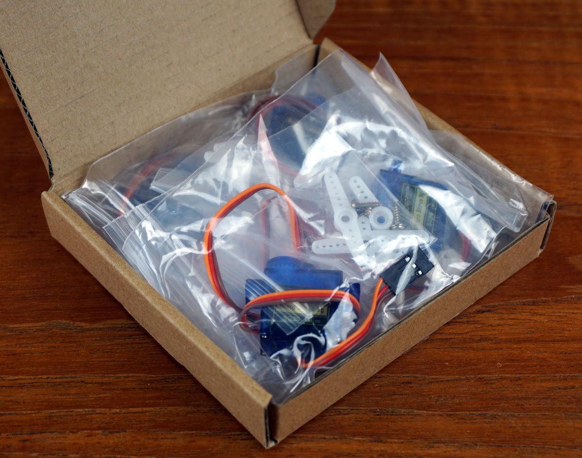 A small box containing four SG90 servos, horns, and screws