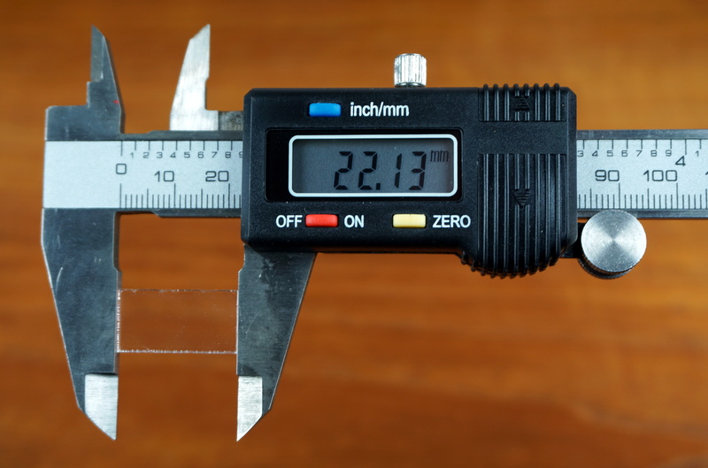 Digital caliper measuring the length of a cutout tile from the servo test stand